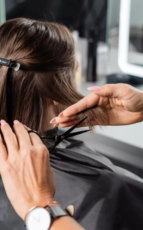 A zoomed image of a hairdresser slowly cutting the hair of the customer